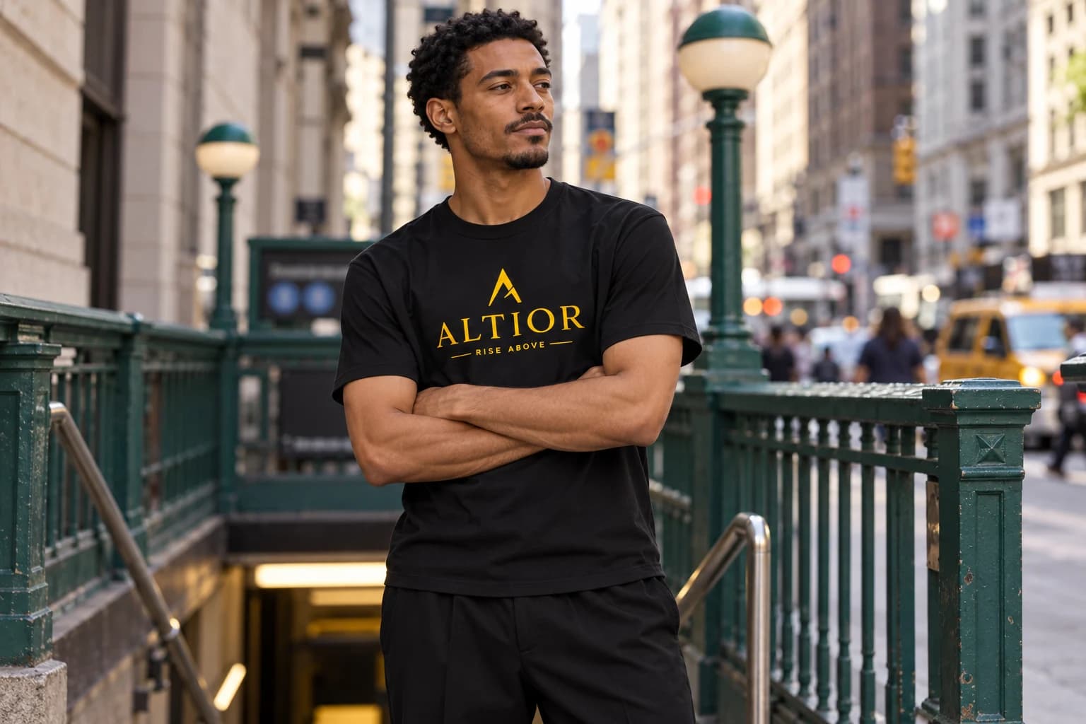 Generated ALTIOR editorial: adult man wearing obsidian gold ascend tee in a New York subway entrance-inspired setting.