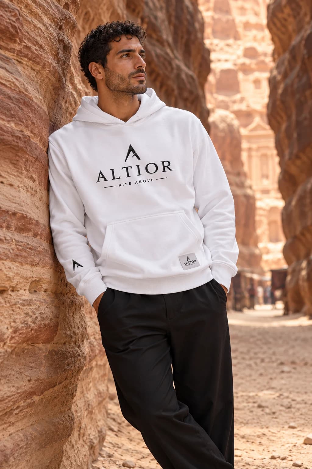 Generated ALTIOR editorial: adult man wearing ghost white summit hoodie in a Petra sandstone passage-inspired setting.