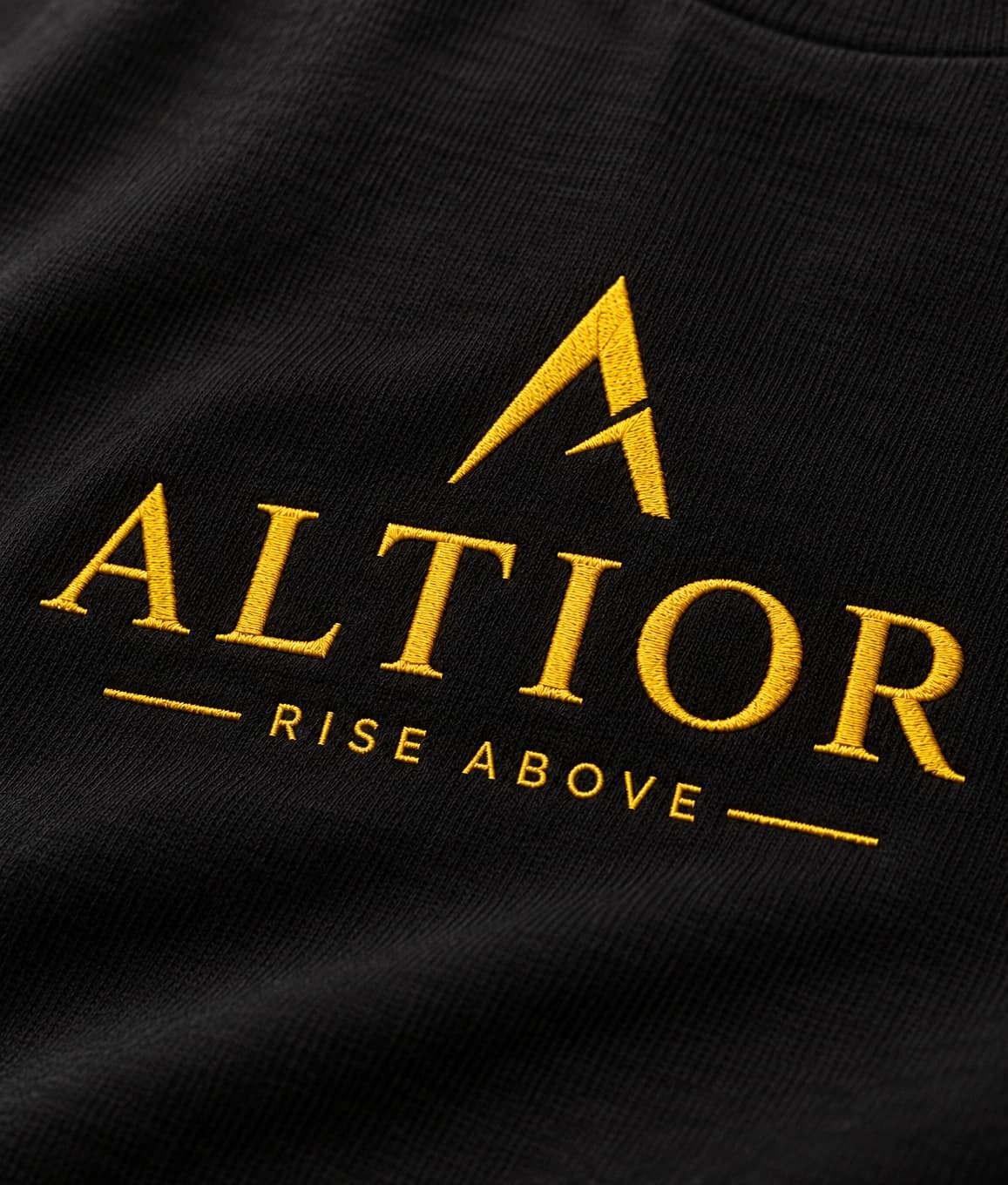 Signature tee — Black with gold detailing, AI-generated embroidered branding close-up