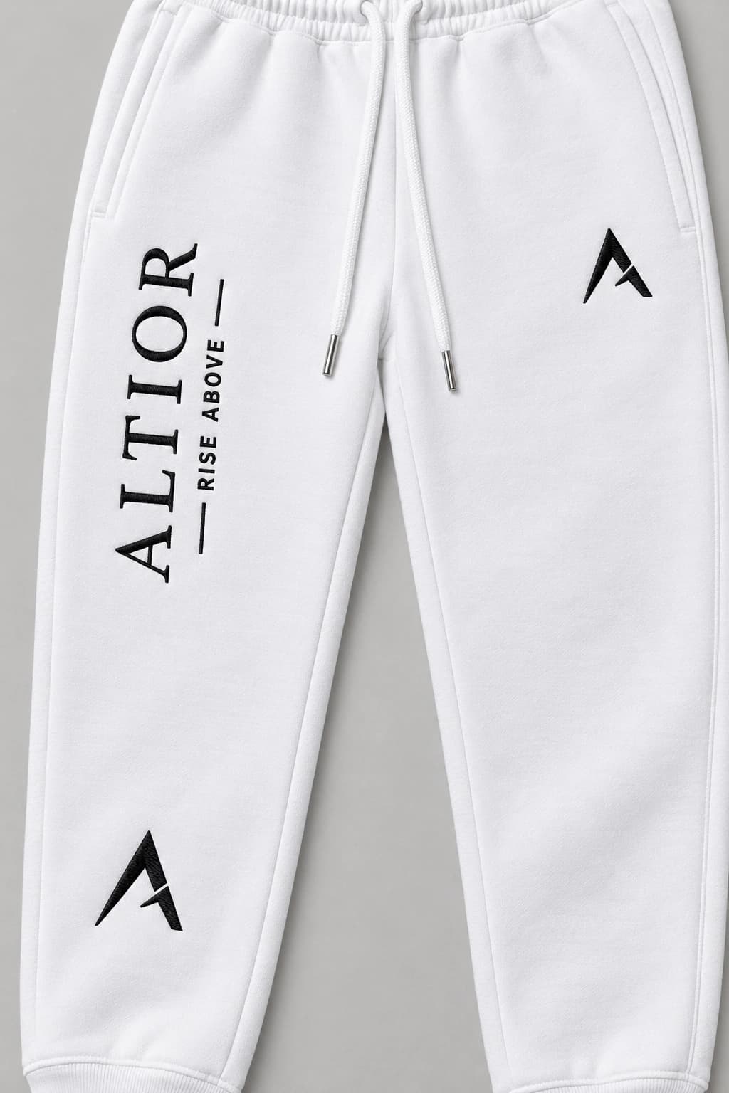 Track pants — White with black detailing, AI-generated embroidered branding close-up