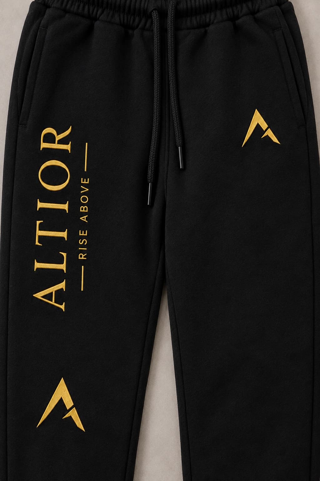 Track pants — Black with gold detailing, AI-generated embroidered branding close-up